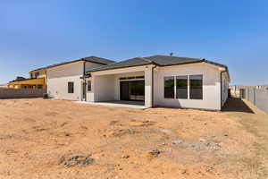Back of property featuring a fenced backyard, a patio area, and stucco siding