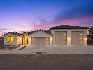 View of front of home featuring an attached garage, stucco siding, driveway, and stone siding