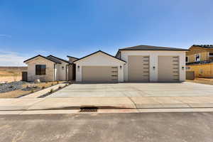 View of front of home featuring concrete driveway, an attached garage, and stucco siding