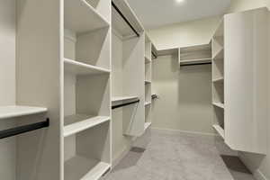 Walk in closet with light colored carpet