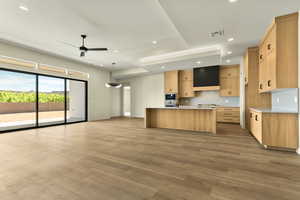 Kitchen with light wood finish cabinetry, a kitchen island with sink, recessed lighting, light wood-style floors, and open floor plan