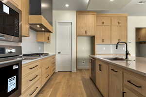 Kitchen featuring stainless steel appliances, light wood finish cabinets, light stone countertops, light wood finished floors, and recessed lighting
