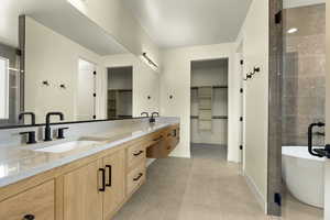 Bathroom featuring double vanity, a stall shower, a soaking tub, a walk in closet, and light tile patterned floors