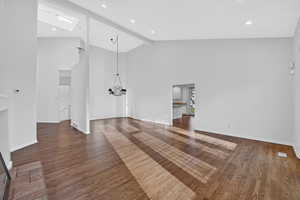 Unfurnished living room featuring dark wood-style flooring, hanging lights, vaulted ceiling, and a ceiling fan