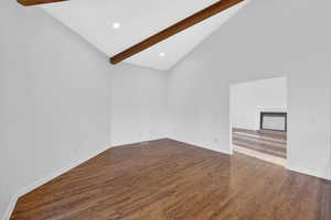 Unfurnished room featuring vaulted ceiling, dark wood finished floors, a fireplace, and recessed lighting