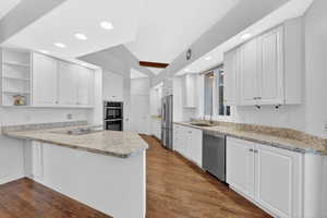 Kitchen featuring a peninsula, open shelves, white cabinets, dark wood finished floors, and recessed lighting