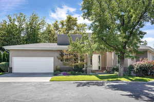 View of front of home featuring an attached garage, driveway, stucco siding, and a front lawn