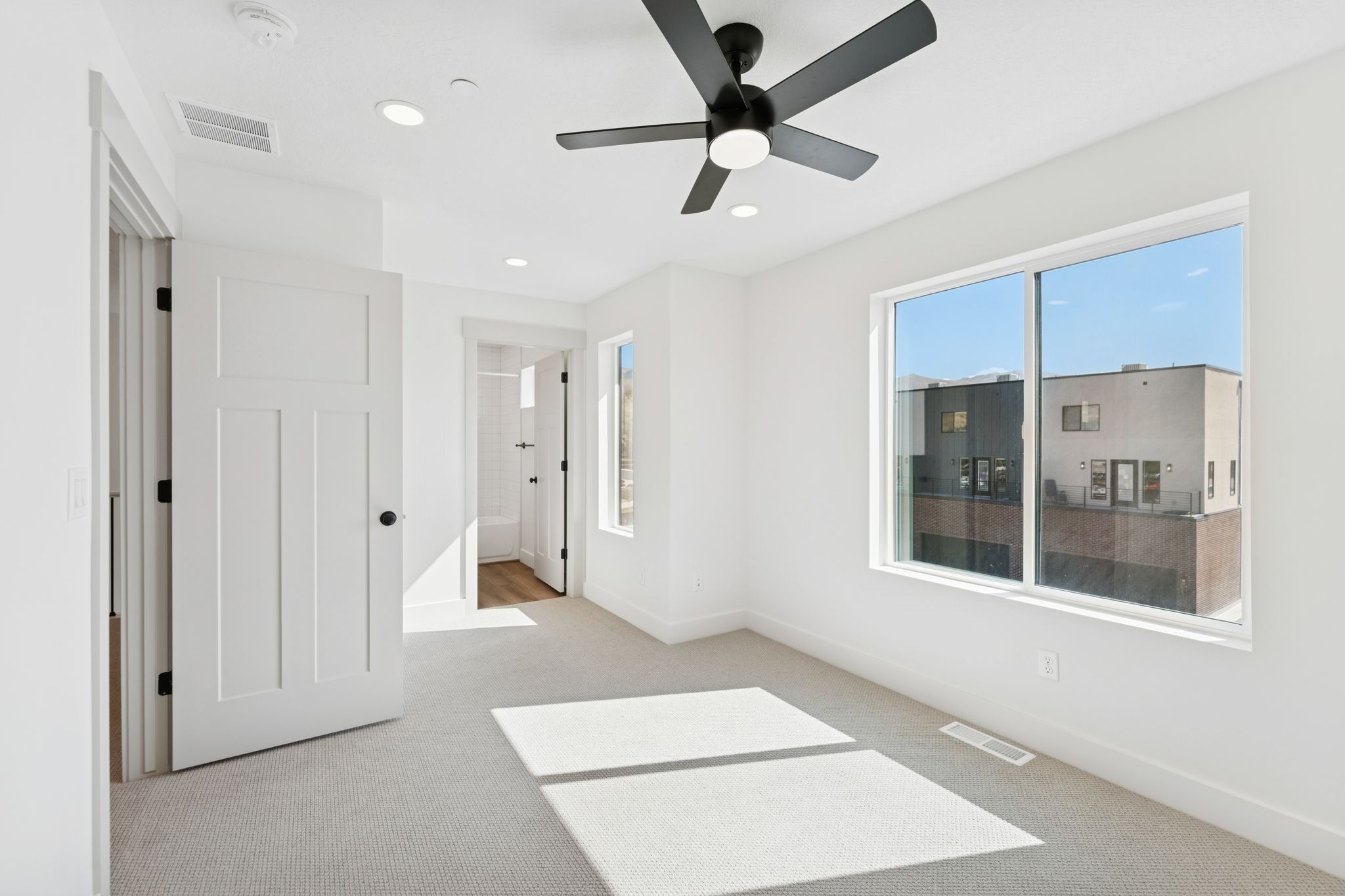 Unfurnished bedroom featuring light colored carpet, ensuite bath, a ceiling fan, and recessed lighting