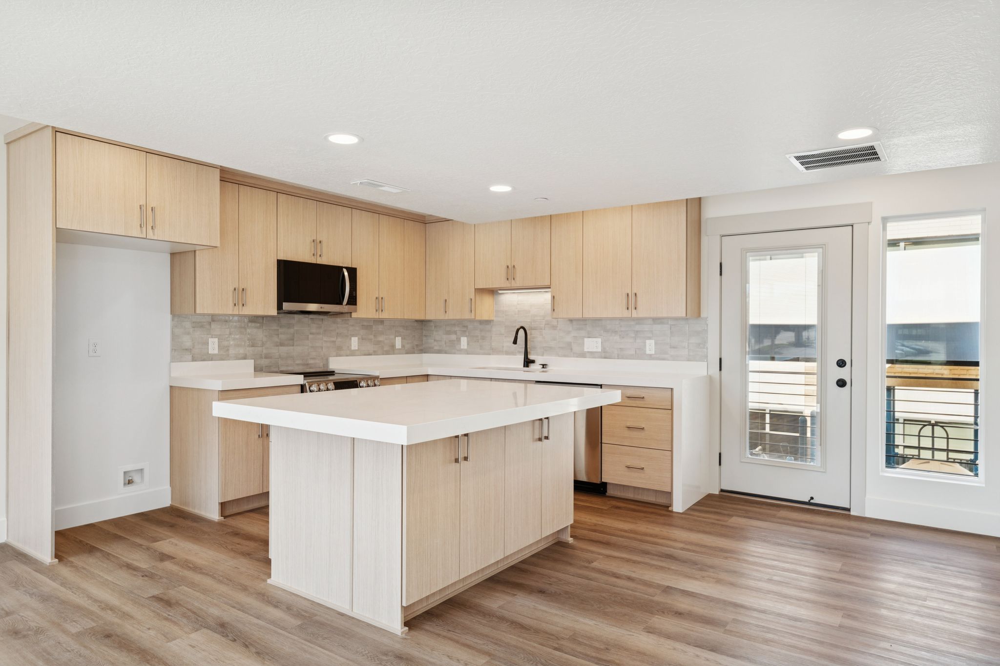 Kitchen with light wood finish cabinets, a kitchen island, stainless steel appliances, light wood-style floors, and recessed lighting
