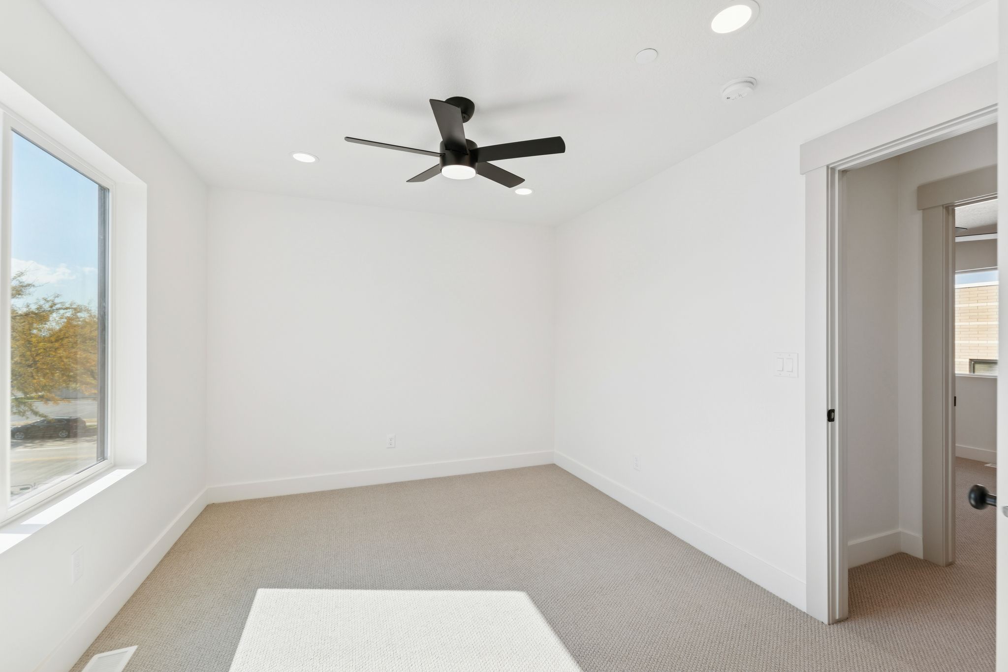 Spare room featuring light colored carpet, a ceiling fan, and recessed lighting