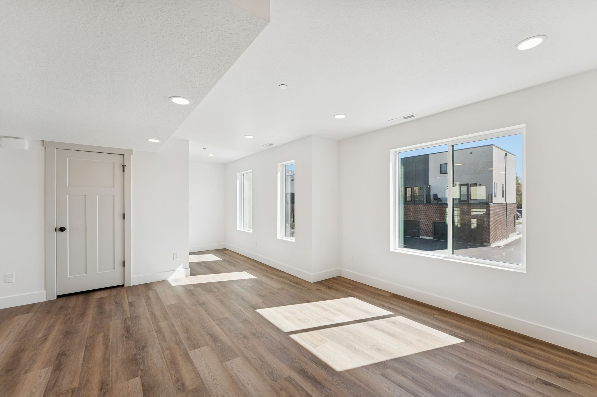 Empty room with light wood-type flooring, healthy amount of natural light, and recessed lighting