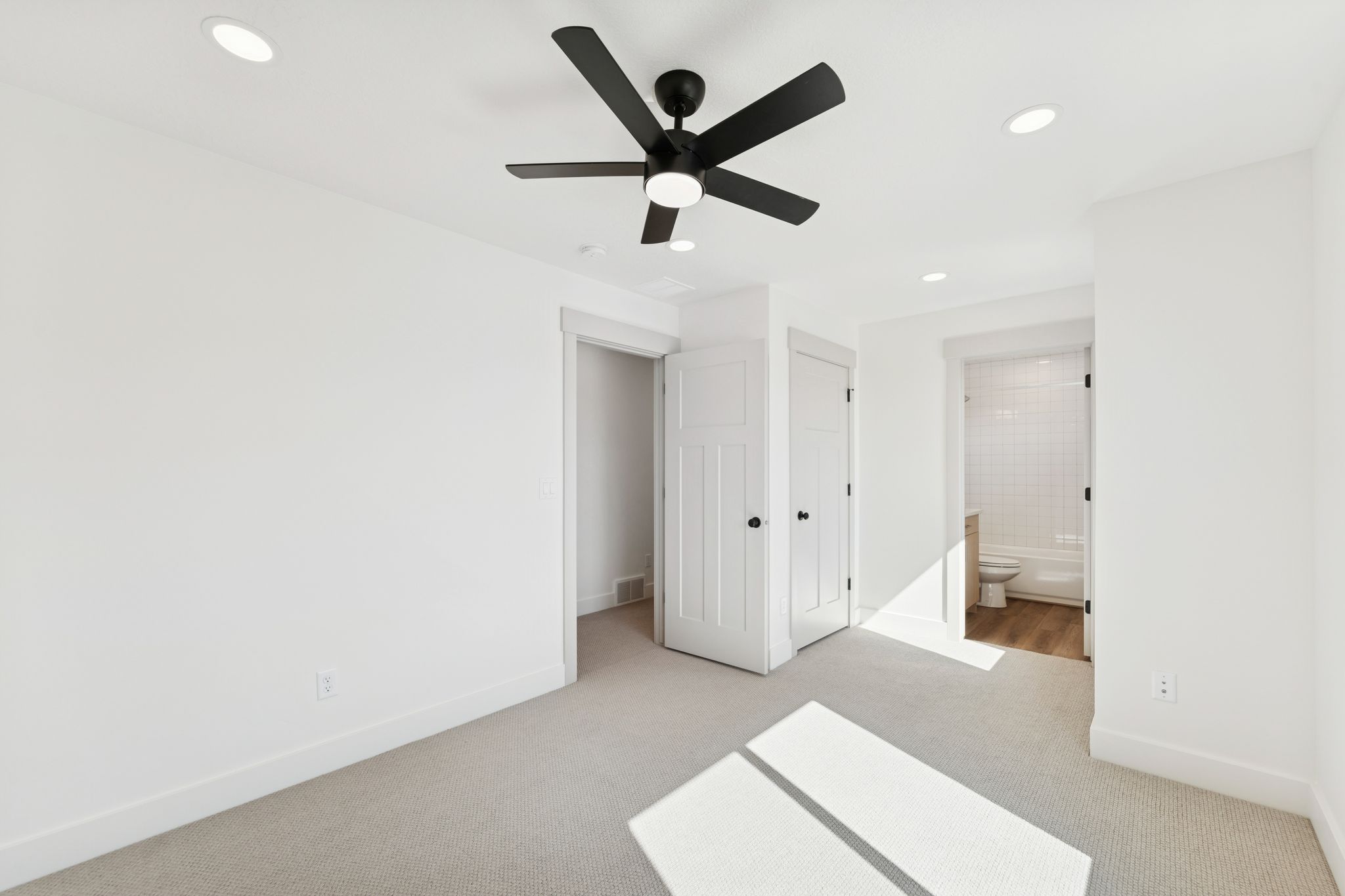 Unfurnished bedroom featuring light colored carpet, a closet, a ceiling fan, recessed lighting, and ensuite bathroom