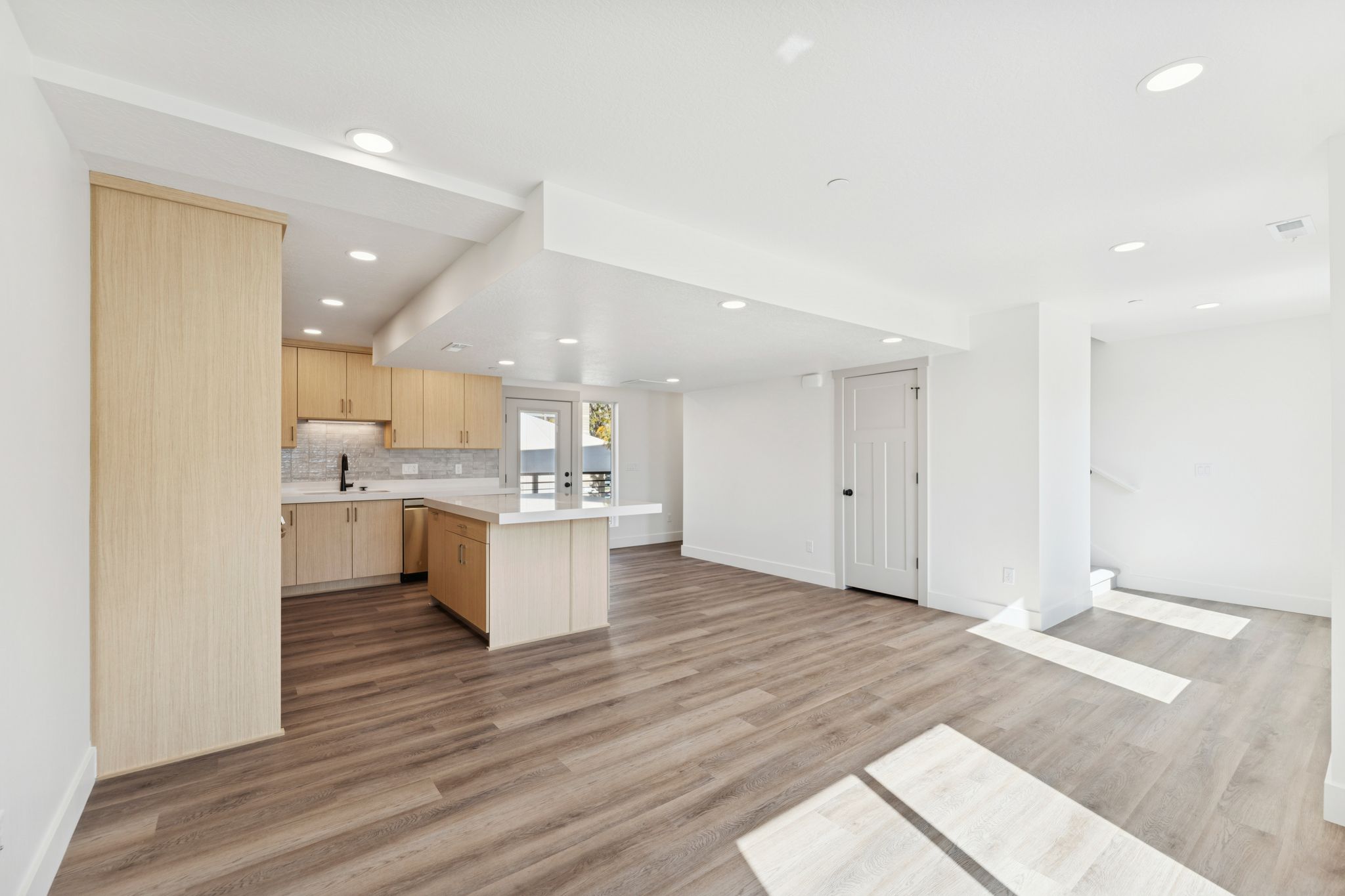 Kitchen with light wood finish cabinetry, light countertops, light wood-style floors, open floor plan, and recessed lighting