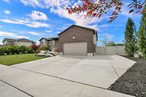 View of front of home with a gate, brick siding, driveway, and an attached garage