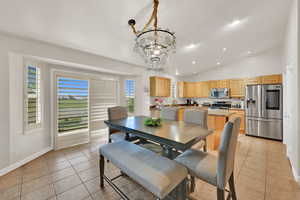 Dining room featuring a chandelier, lofted ceiling, and light tile patterned flooring