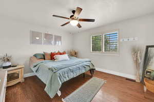 Bedroom with a textured ceiling, dark wood finished floors, and a ceiling fan