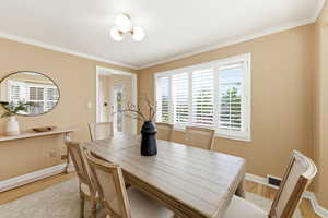 Dining room featuring light wood-style floors, healthy amount of natural light, and crown molding