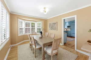 Dining area featuring light wood-type flooring and crown molding