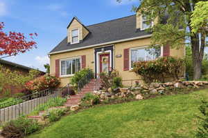 Cape cod home featuring roof with shingles and brick siding
