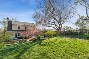 Rear view of house featuring a patio area, a chimney, a fenced backyard, and a shingled roof