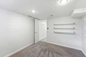 Empty room with carpet flooring and a textured ceiling
