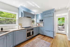Kitchen featuring light stone countertops, stainless steel appliances, light wood finished floors, tasteful backsplash, and recessed lighting