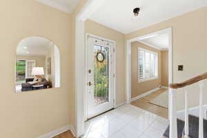 Foyer entrance with crown molding, light tile patterned floors, and arched walkways