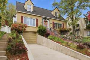 Cape cod house featuring a shingled roof, brick siding, a garage, and driveway