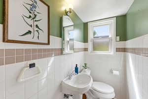 Bathroom with a wainscoted wall and tile walls