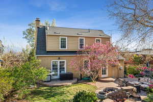 Rear view of house featuring a patio, a chimney, an outdoor living space with a fire pit, and brick siding