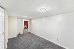 Finished below grade area featuring a textured ceiling and dark carpet