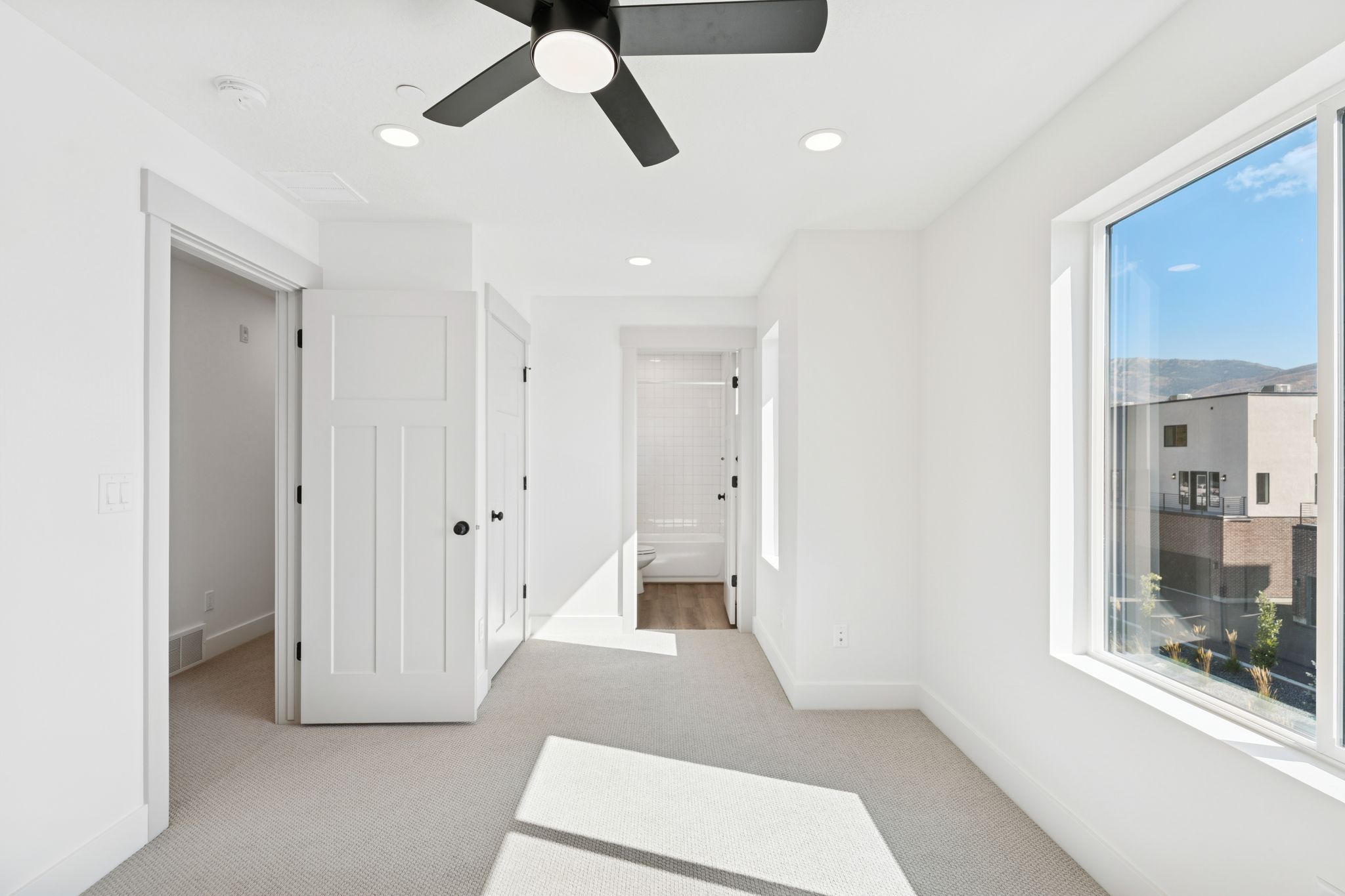 Unfurnished bedroom featuring connected bathroom, light colored carpet, a ceiling fan, and recessed lighting