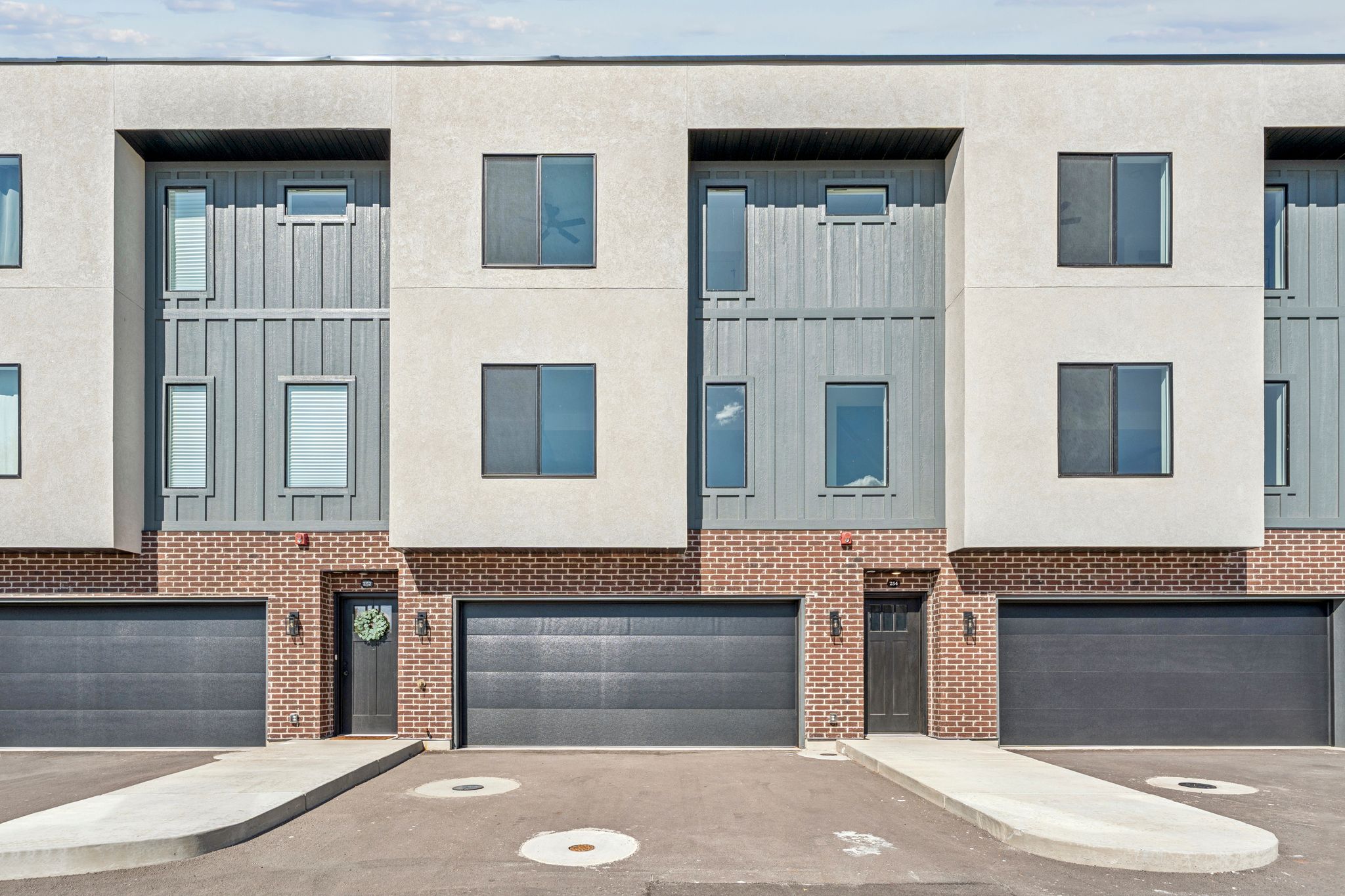 View of front of house featuring an attached garage, brick siding, board and batten siding, and driveway