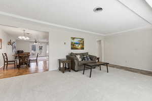 Living area featuring a textured ceiling, light colored carpet, a chandelier, and a ceiling fan