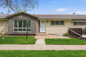 Ranch-style townhouse featuring brick siding, roof with shingles, and a front yard