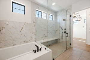Full bathroom featuring a garden tub, a marble finish shower, and light tile patterned floors