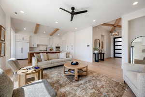 Living room featuring a ceiling fan, light wood finished floors, lofted ceiling, and hanging lights