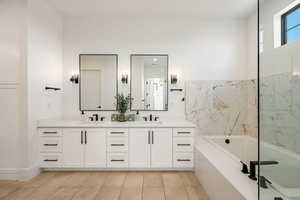 Full bathroom featuring double vanity, a garden tub, and light tile patterned flooring