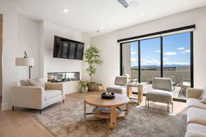 Living room featuring light wood-type flooring, recessed lighting, and a multi sided fireplace