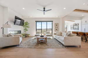 Living room with recessed lighting, light wood-type flooring, ceiling fan, and beamed ceiling