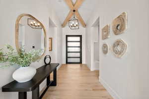 Entrance foyer featuring light wood-style floors, beam ceiling, and suspended lighting