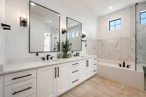 Full bath featuring healthy amount of natural light, double vanity, a garden tub, a marble finish shower, and recessed lighting