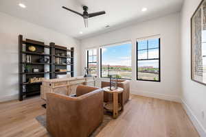 Living area featuring light wood-style floors, a ceiling fan, and recessed lighting