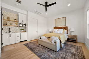 Bedroom featuring light wood-style flooring, a ceiling fan, wet bar, and recessed lighting