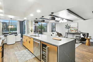 Kitchen featuring beverage cooler, open floor plan, appliances with stainless steel finishes, and a waterfall countertop