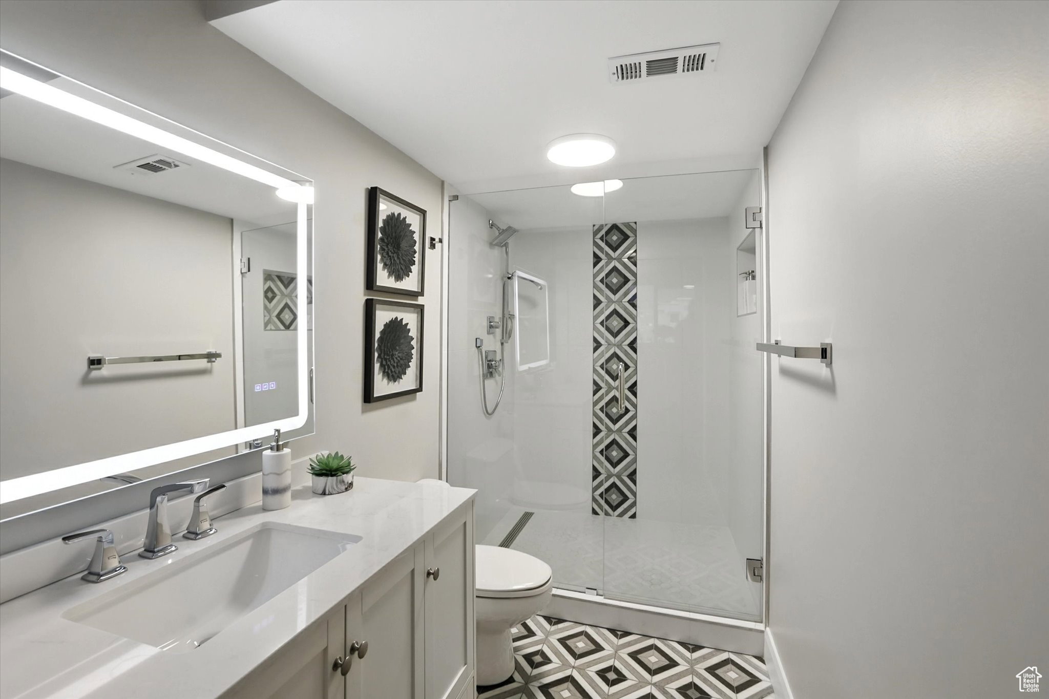 Bathroom suite on main level featuring vanity, a stall shower, and tile patterned floors