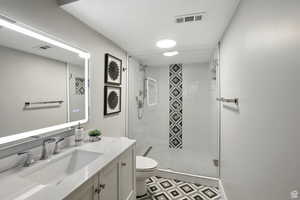 Bathroom suite on main level featuring vanity, a stall shower, and tile patterned floors