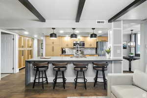 Kitchen with light cabinets, decorative backsplash, stainless steel appliances, and beamed ceiling