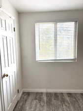 Empty room with baseboards and dark wood-style flooring
