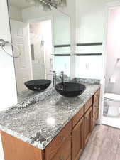 Bathroom with vanity, light wood-style floors, and a marble finish shower